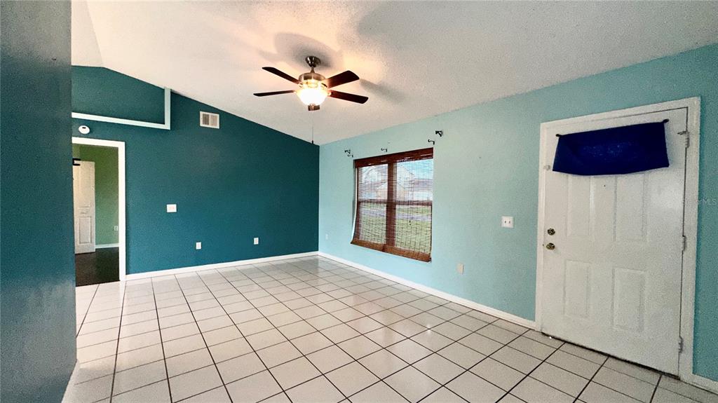 A room with white tiled floors, a vaulted ceiling, and walls painted teal and light blue — 620 BROCKTON DRIVE, KISSIMMEE, FL