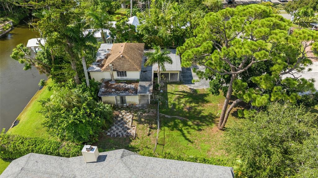 An aerial view shows a house with a brown roof, a canal, and large trees — 103 40TH STREET COURT NW, BRADENTON, FL