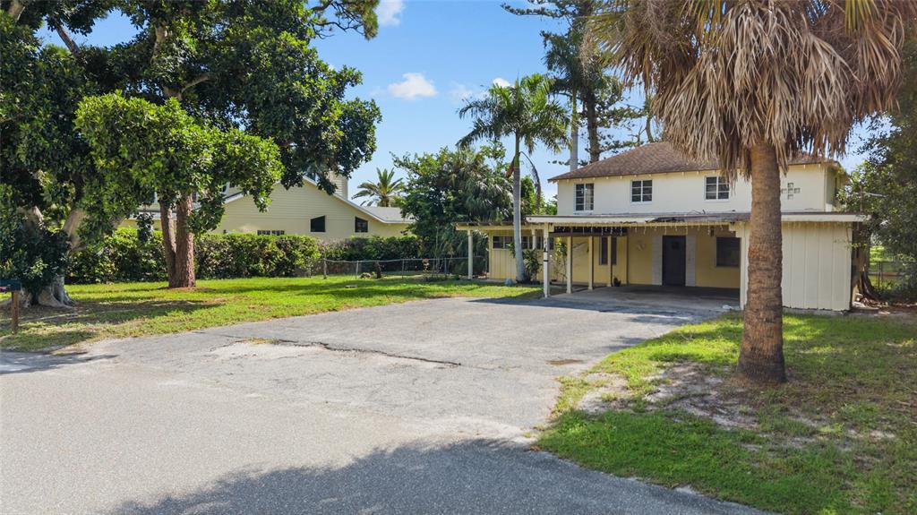 A two-story house with a paved driveway, a covered carport, and surrounding palm trees — 103 40TH STREET COURT NW, BRADENTON, FL