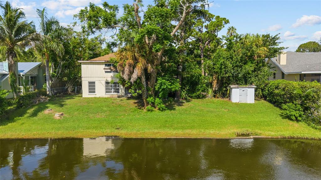 A two-story house with a backyard lawn sits along a canal next to a shed — 103 40TH STREET COURT NW, BRADENTON, FL