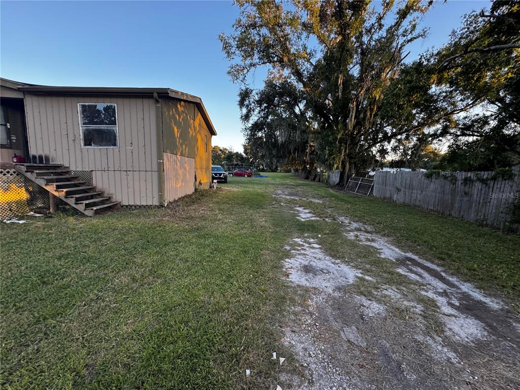 A side view of a mobile home with wooden stairs and a dirt driveway — 33346 ARTHUR DRIVE, WESLEY CHAPEL, FL