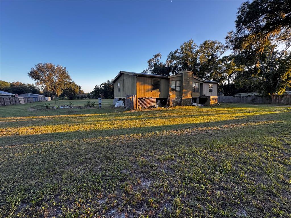 A single-story mobile home with a chimney sits on a large, grassy lot — 33346 ARTHUR DRIVE, WESLEY CHAPEL, FL