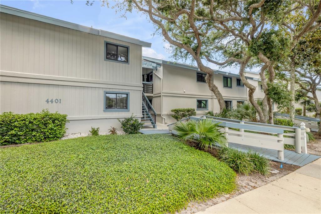 A two-story apartment building with light-colored siding, a wooden ramp, and a grassy lawn — 4401 SEA MIST DRIVE UNIT 102, NEW SMYRNA BEACH, FL