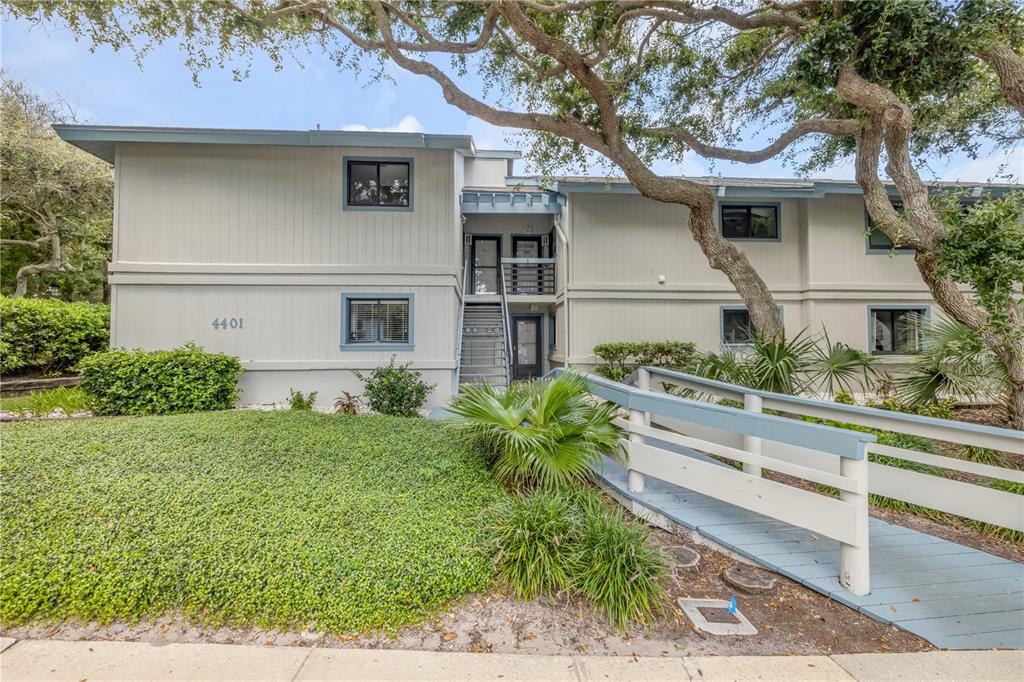 A two-story apartment building with light gray siding, a central staircase, and a wooden ramp — 4401 SEA MIST DRIVE UNIT 102, NEW SMYRNA BEACH, FL
