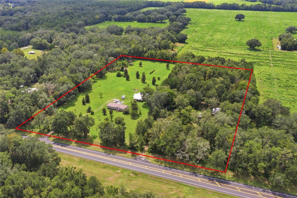 An aerial view shows a house and outbuildings on a large, partially wooded rural lot — 7412 NW STATE ROAD 45, HIGH SPRINGS, FL