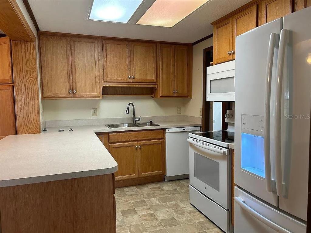A kitchen with oak cabinets, white appliances, laminate countertops, and a vinyl tile floor — 7901 CASTILE ROAD, SEBRING, FL