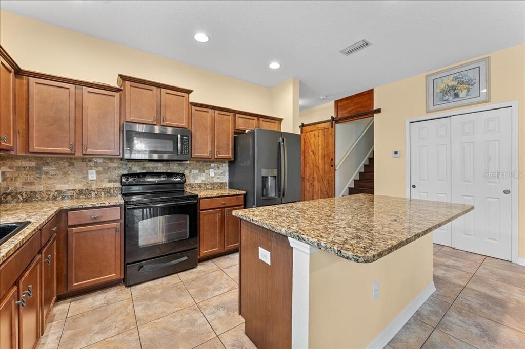 A kitchen features wood cabinets, granite countertops, stainless steel appliances, and a central island — 8005 112TH AVENUE E, PARRISH, FL
