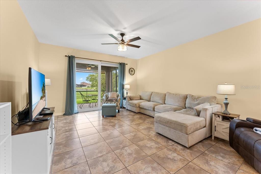 A living room features tile flooring, a large sectional sofa, and sliding glass doors — 8005 112TH AVENUE E, PARRISH, FL