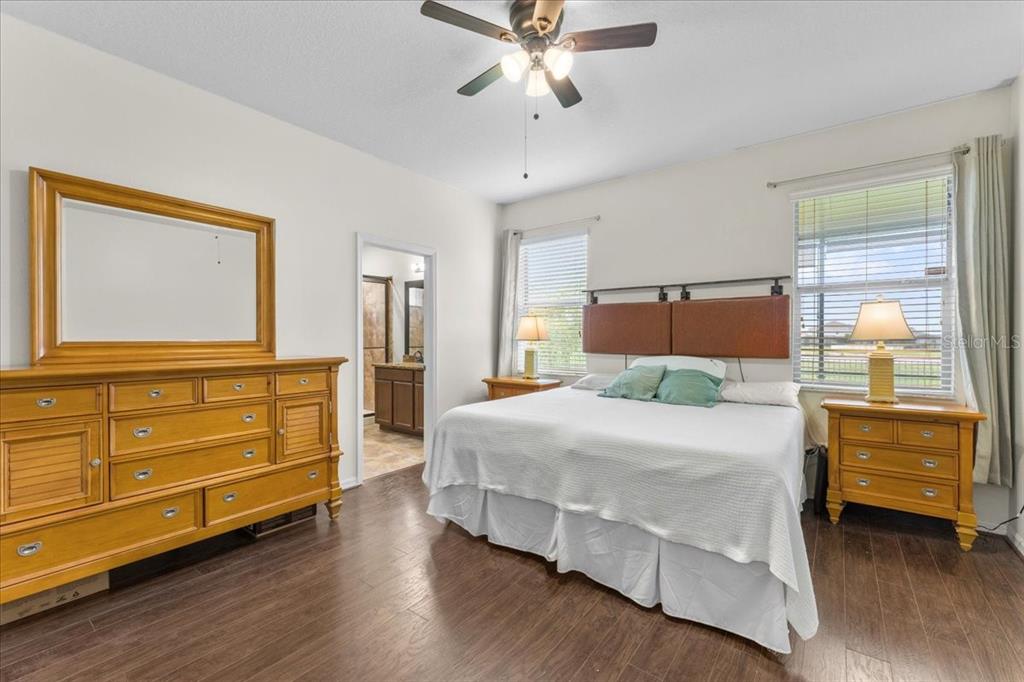 A bedroom features a king bed, wooden furniture, and dark wood flooring — 8005 112TH AVENUE E, PARRISH, FL