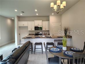 A kitchen with white cabinets and a breakfast bar overlooks a dining area and living room — 239 BITTERN LOOP, INVERNESS, FL