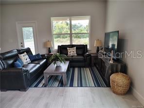 A living room features two black leather sofas, a wooden coffee table, and a television console — 239 BITTERN LOOP, INVERNESS, FL