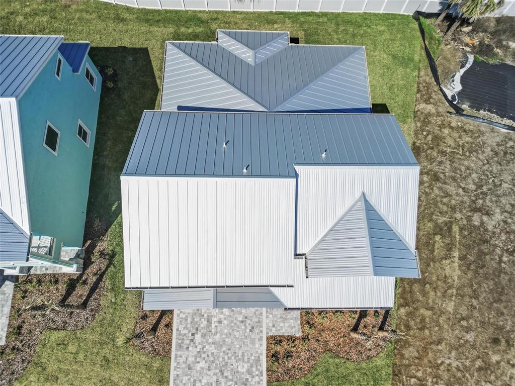 An aerial view shows the metal roofs of two adjacent houses and a paved driveway — 112 BEACHVIEW DRIVE, ORMOND BEACH, FL