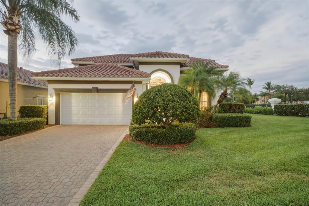 A single-story house with a tiled roof, white garage door, and manicured landscaping — 1110 3RD STREET E, PALMETTO, FL