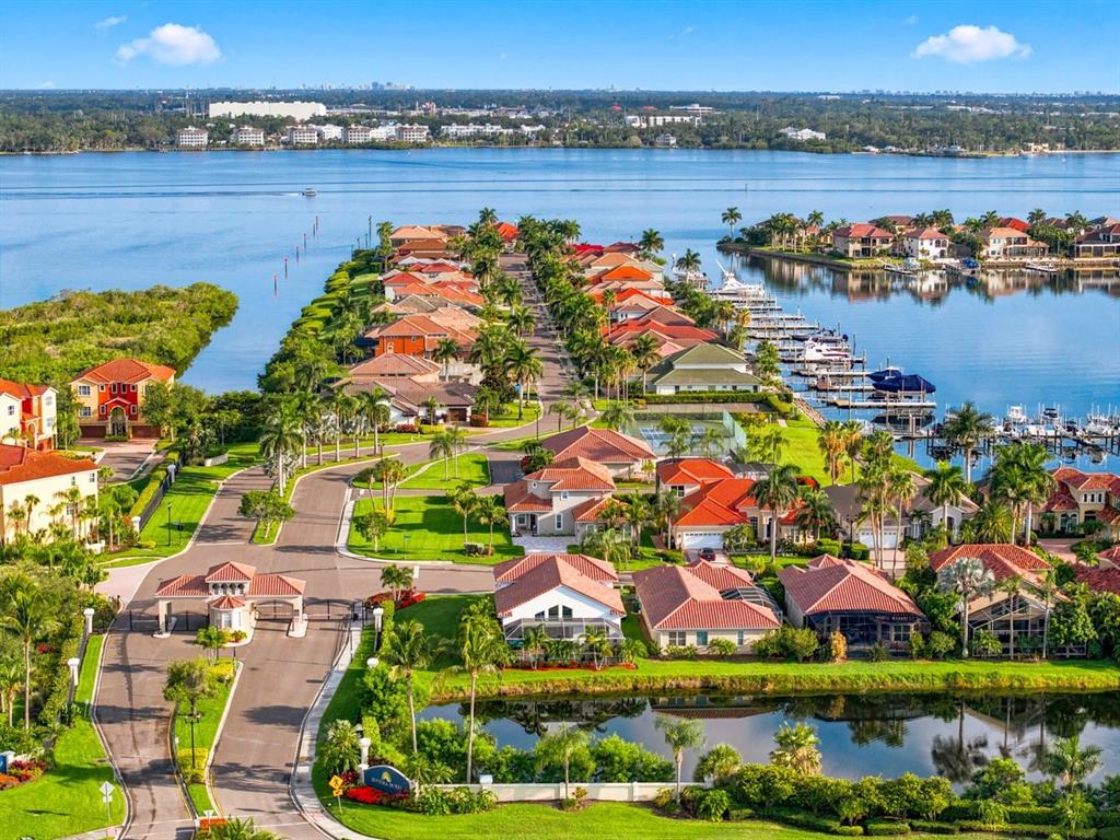 An aerial view of a gated waterfront residential community with houses, palm trees, and docks — 1110 3RD STREET E, PALMETTO, FL