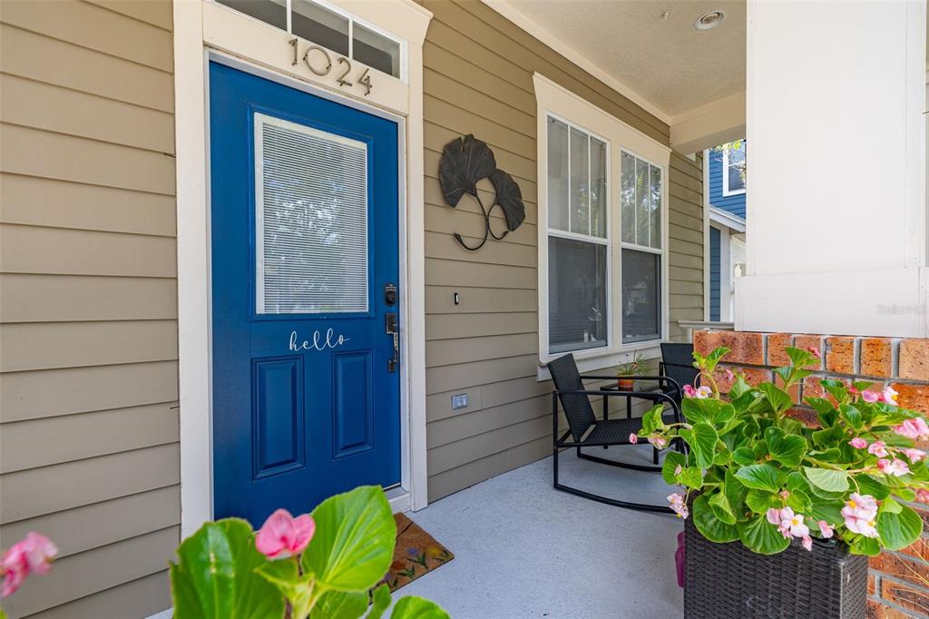 A two-story tan house with a front porch, attached garage, and a red house adjacent — 1024 BANKS ROSE STREET, CELEBRATION, FL