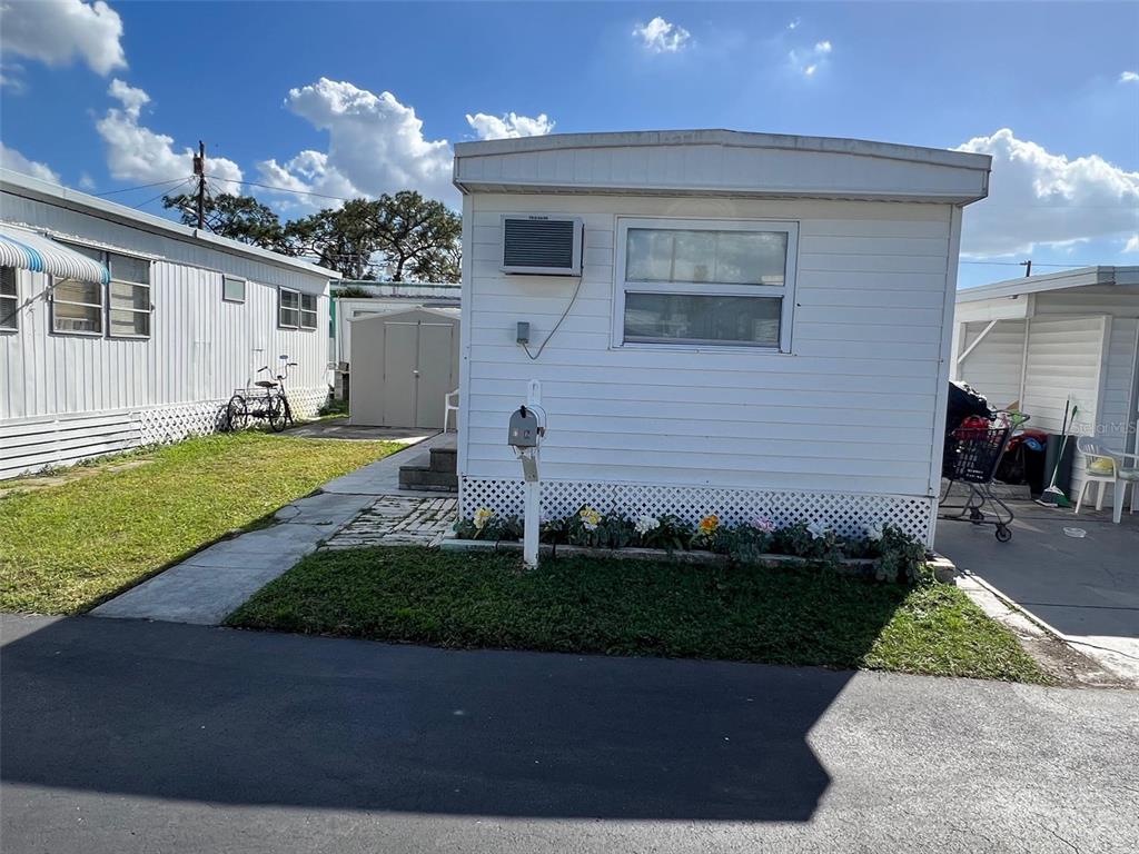 The exterior of a white mobile home features a window air conditioning unit and a mailbox — 12674 SEMINOLE BOULEVARD UNIT C6, LARGO, FL