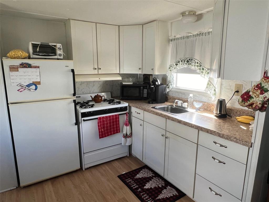A kitchen features white cabinets, a white stove, a refrigerator, and a window above the sink — 12674 SEMINOLE BOULEVARD UNIT C6, LARGO, FL