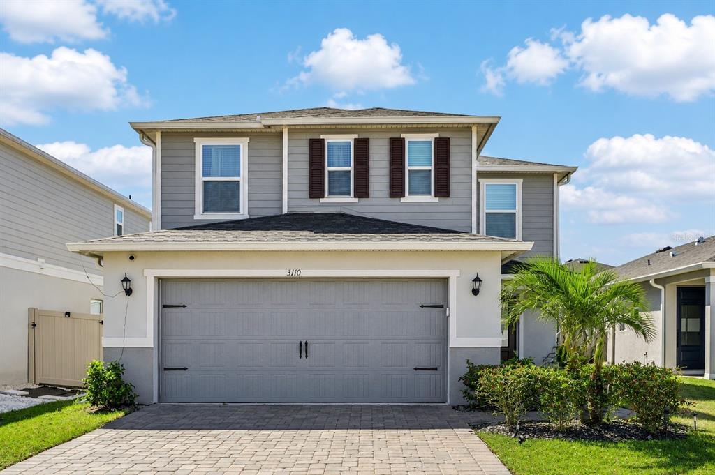 A two-story house with gray siding, a tan stucco garage, and a paved driveway — 3110 SANCTUARY DRIVE, CLERMONT, FL