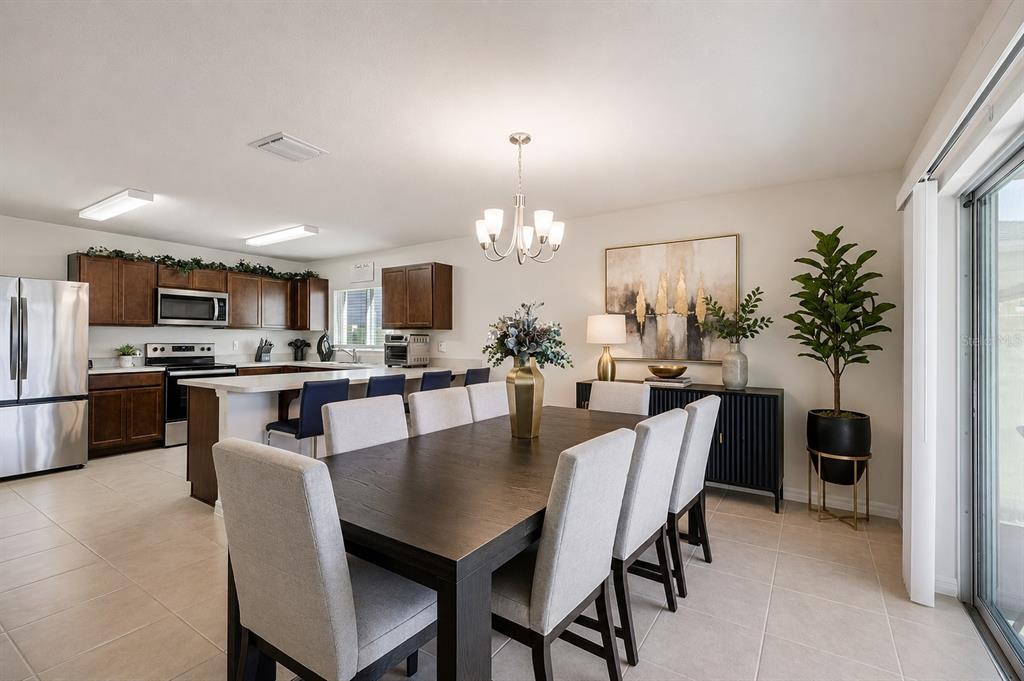 A dining area with a dark wood table and chairs sits adjacent to a modern kitchen — 3110 SANCTUARY DRIVE, CLERMONT, FL