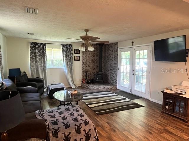 A living room features wood-look flooring, a wood-burning stove, a ceiling fan, and glass doors — 9559 SE STATE ROAD 100, STARKE, FL
