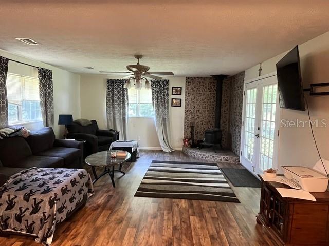 A living room features wood-look flooring, a wood-burning stove, and a ceiling fan — 9559 SE STATE ROAD 100, STARKE, FL