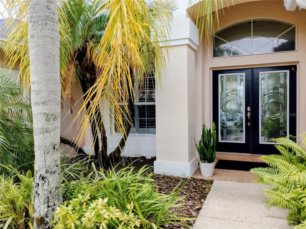 A front entryway features double glass doors, a transom window, and surrounding tropical landscaping — 11939 56TH STREET E, PARRISH, FL