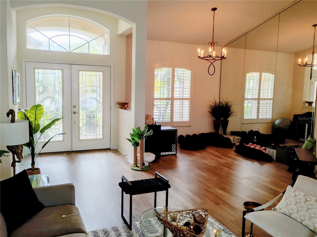 A bright entryway and living area feature wood-look flooring, a large mirror, and double doors — 11939 56TH STREET E, PARRISH, FL