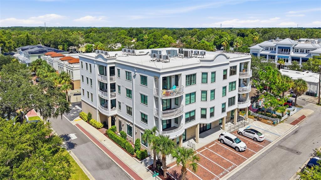 An aerial view of a multi-story white apartment building with balconies and a brick parking lot — 231 2ND STREET S UNIT 202, SAFETY HARBOR, FL