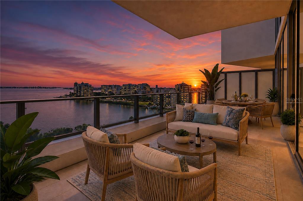 A furnished balcony overlooks a sunset view of a bay and city skyline — 1155 N GULFSTREAM AVENUE UNIT 806, SARASOTA, FL