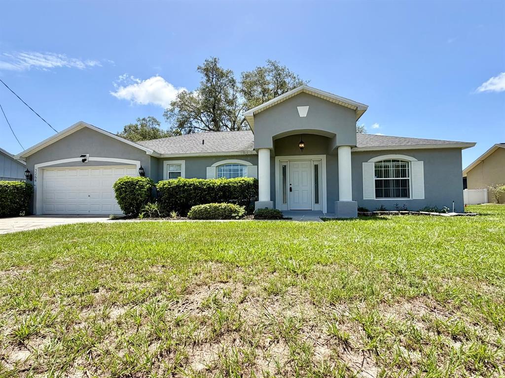A single-story gray house with a two-car garage and a covered front entryway — 3264 DELTONA BOULEVARD, SPRING HILL, FL