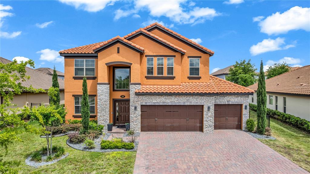 A two-story stucco house with a stone facade, tile roof, and a three-car garage — 239 LUGANO WAY, DEBARY, FL