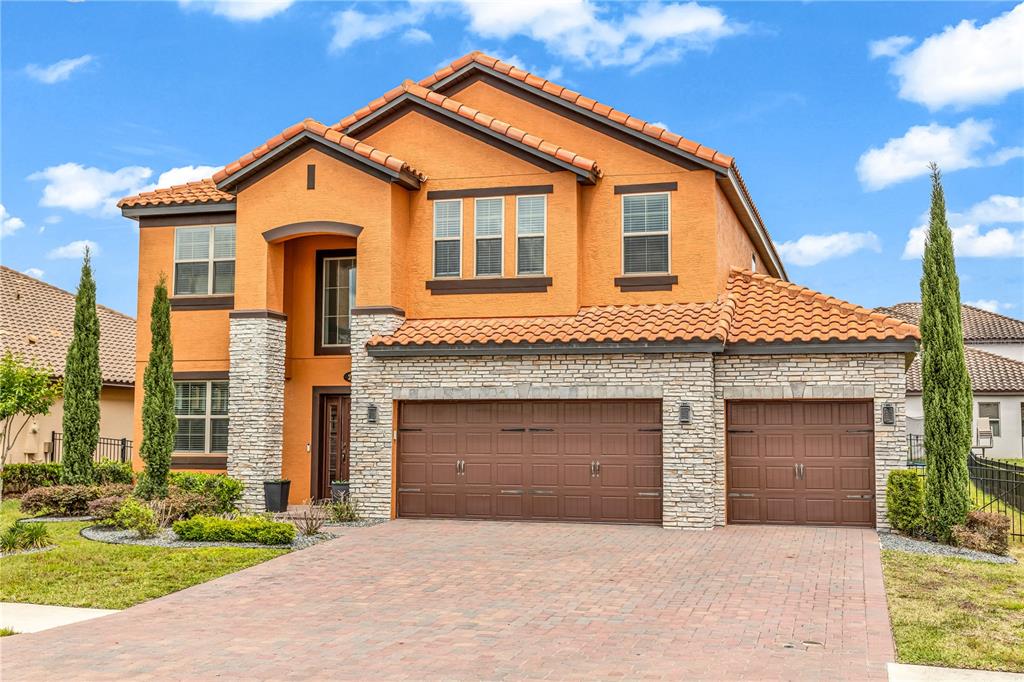 A two-story house with orange stucco, stone accents, a tile roof, and a three-car garage — 239 LUGANO WAY, DEBARY, FL