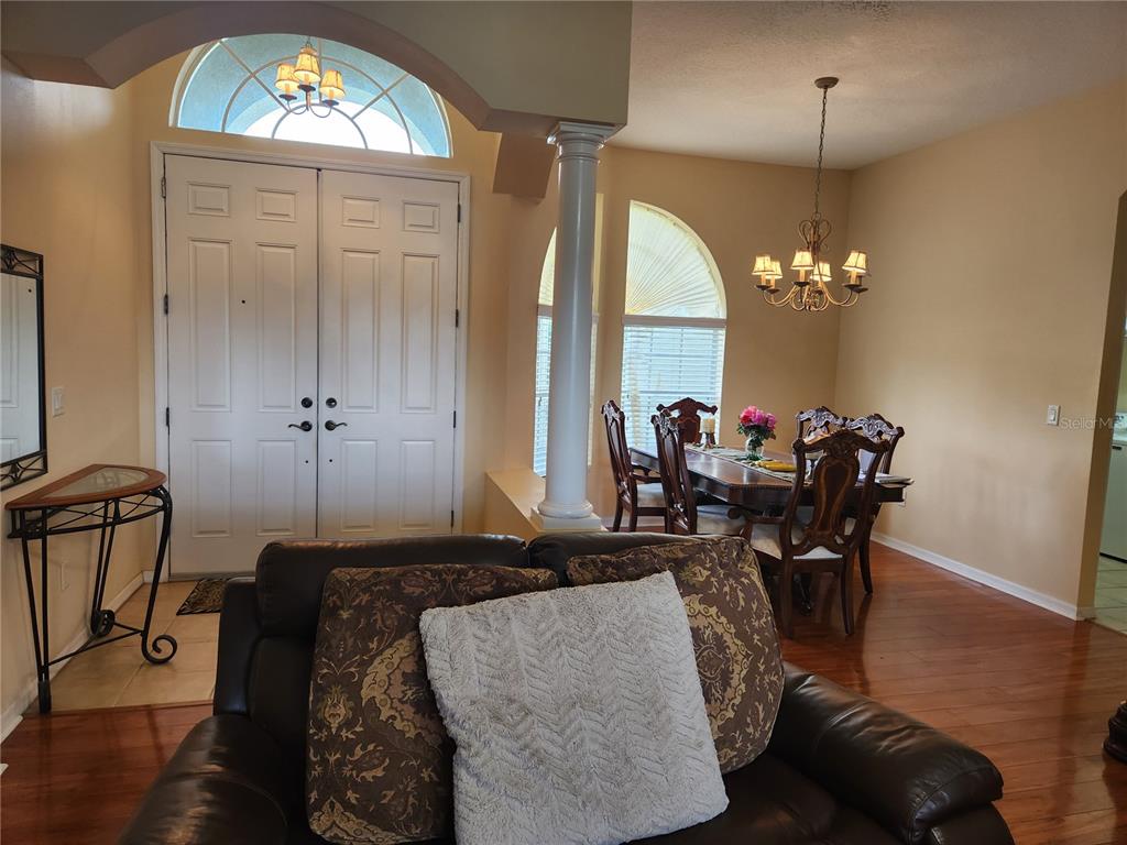 A living room with a leather sofa faces a dining area and a double front door — 1629 CANOE DRIVE, LUTZ, FL