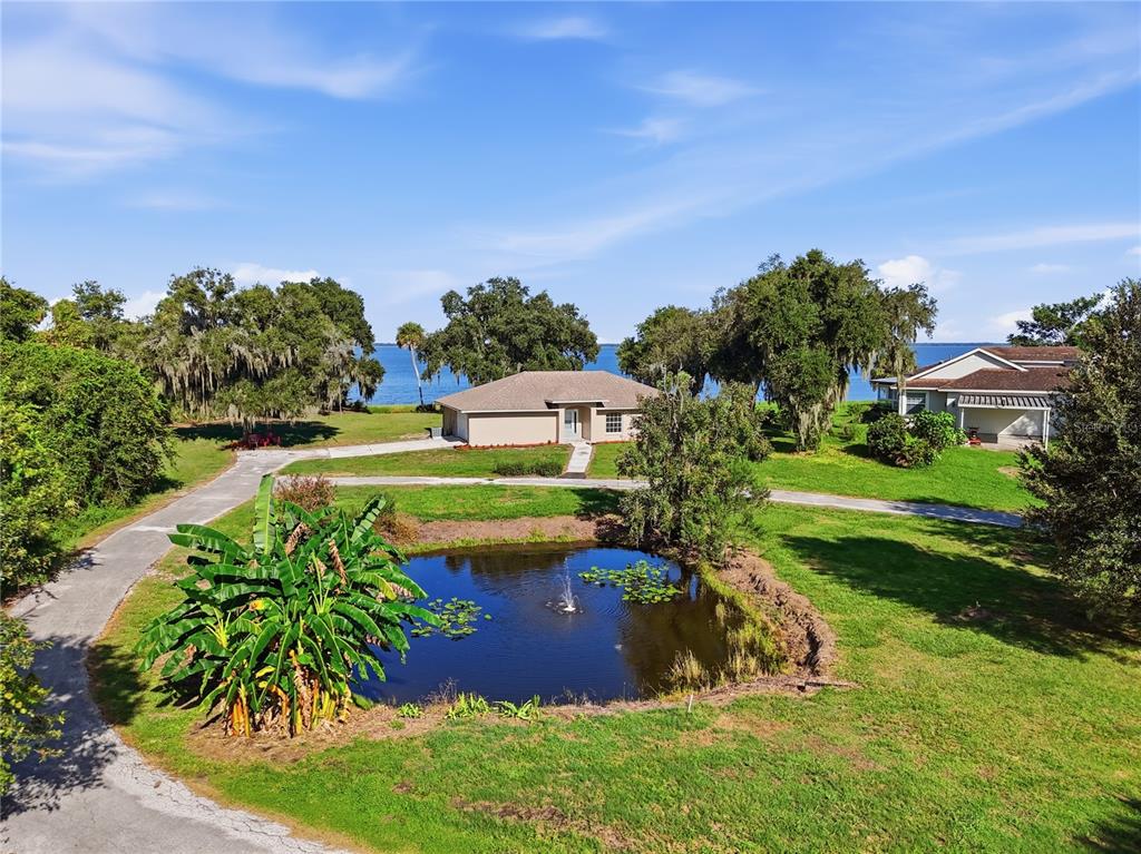 An aerial view shows a house with a pond, fountain, and driveway near a lake — 3005 SCRUB OAK LANE, LAKE WALES, FL
