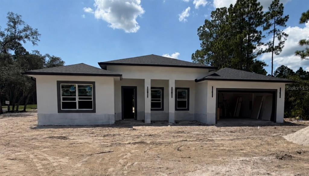 A newly constructed single-story house with a white stucco exterior and a two-car garage — 40401 ROYAL TRAILS ROAD, EUSTIS, FL