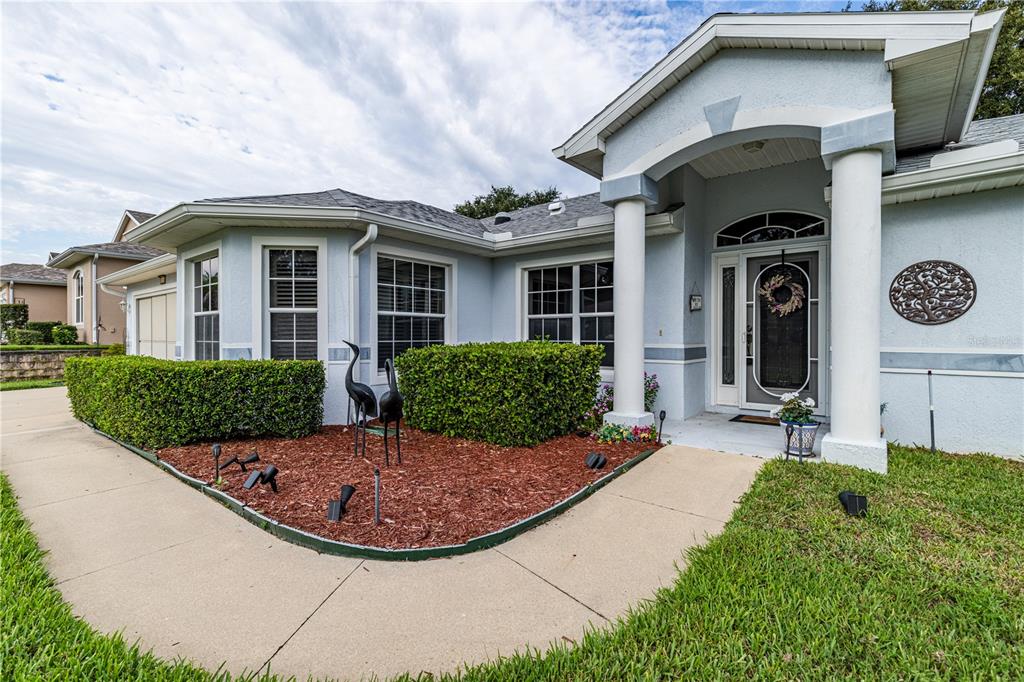A light blue house exterior features a covered entryway with white columns and landscaping — 5154 INDIAN OCEAN LOOP, TAVARES, FL