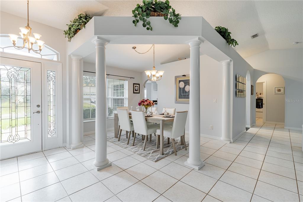 A dining area features white columns, tile flooring, and a chandelier under a decorative soffit — 5154 INDIAN OCEAN LOOP, TAVARES, FL