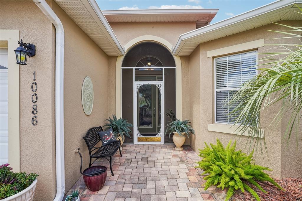 A single-story house with a tan stucco exterior, red roof, and a paved driveway — 10086 KETCH KAY LANE, OXFORD, FL