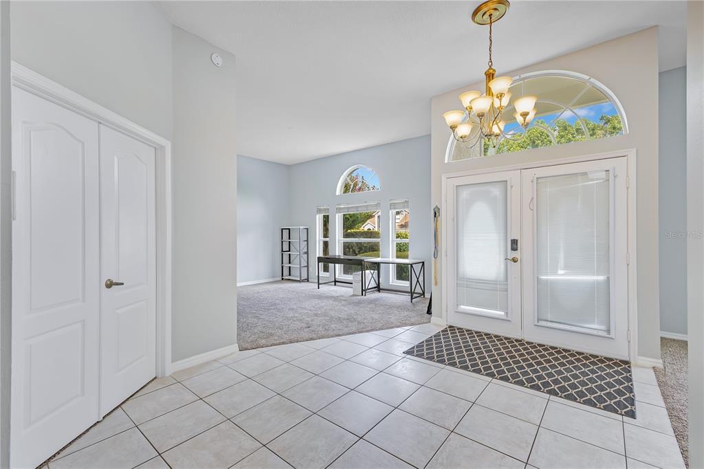 A carpeted room features high ceilings, large windows, a desk, and a white front door — 514 KEY COURT, ORLANDO, FL
