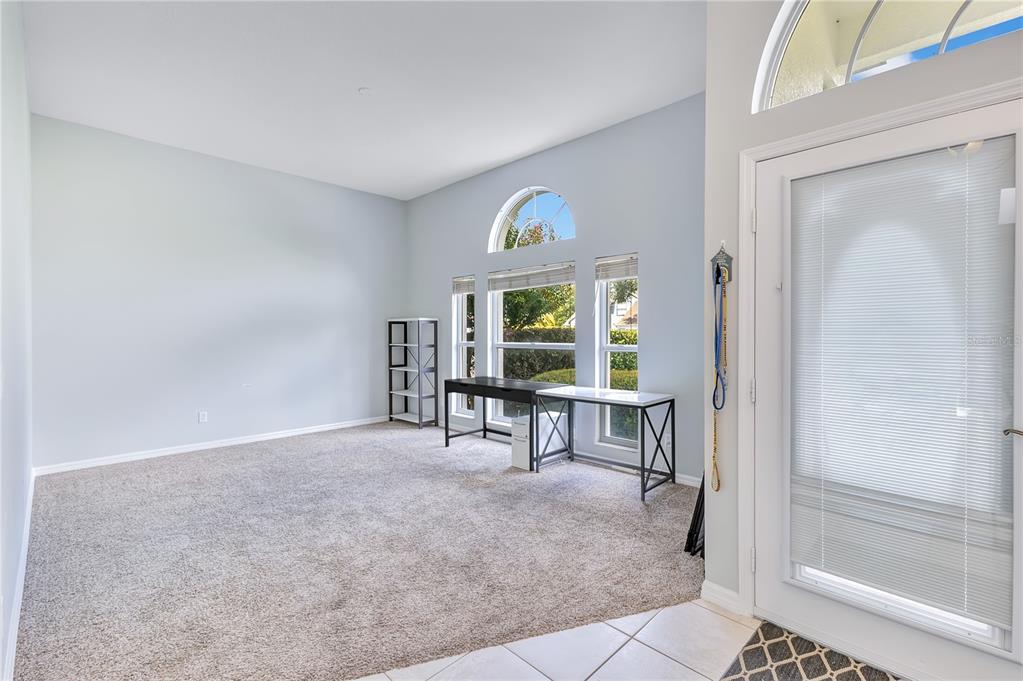 A living room with carpeted floors, large arched windows, a desk, and a tiled entryway — 514 KEY COURT, ORLANDO, FL