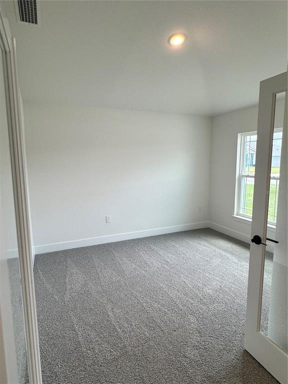 An empty room with white walls, gray carpet, and a glass-paneled door — 2671 AVERLAND LOOP, NORTH PORT, FL
