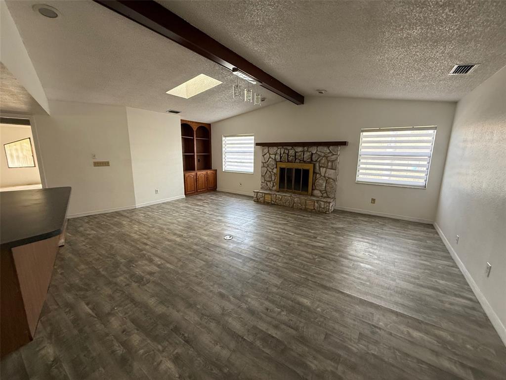 A living room features wood-look flooring, a stone fireplace, and a built-in wooden cabinet — 5312 SUWANNEE ROAD, WEEKI WACHEE, FL