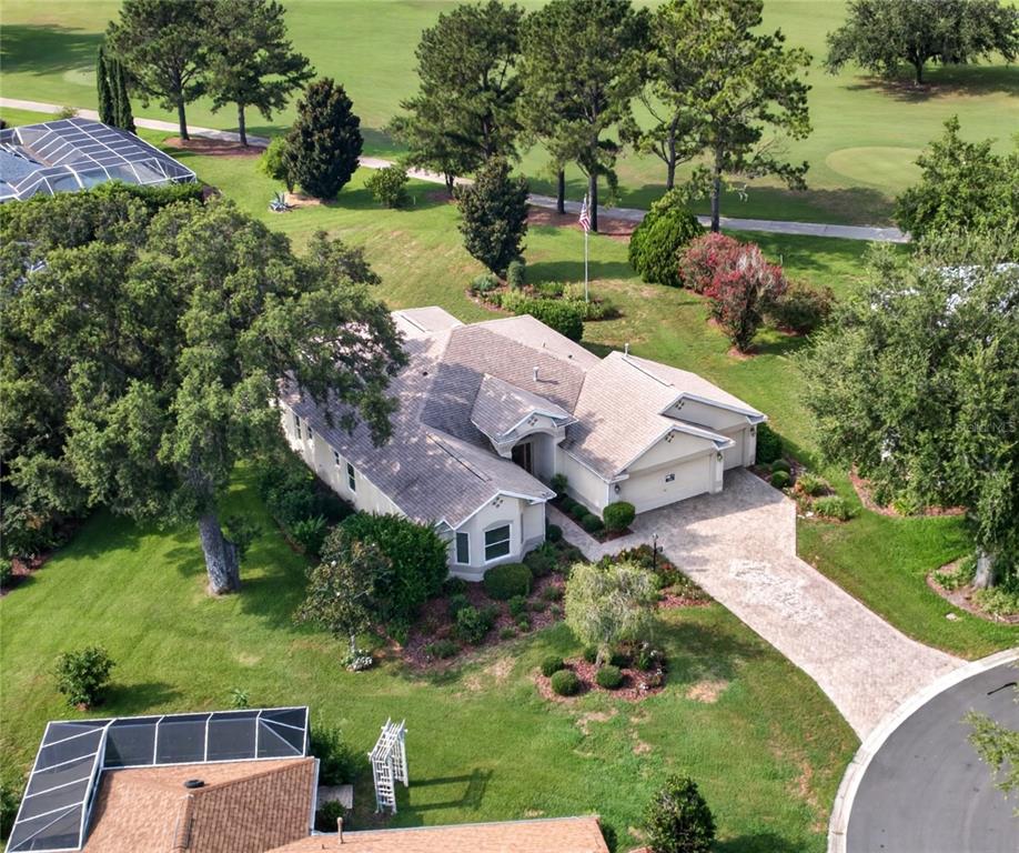 A single-story house with a beige stucco exterior, a paved driveway, and a landscaped yard — 16815 SE 85TH BELKNAP AVENUE, THE VILLAGES, FL