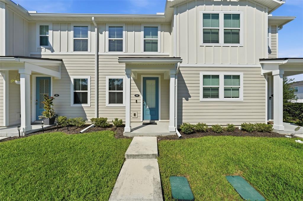 The exterior of a two-story townhouse with light siding, blue doors, and a front walkway — 46 AXEL FALL DRIVE, ST JOHNS, FL