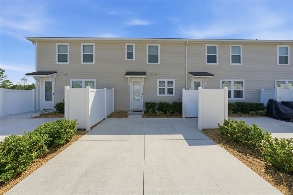 The exterior of a two-story townhouse features beige siding, white trim, and a concrete driveway — 46 AXEL FALL DRIVE, ST JOHNS, FL