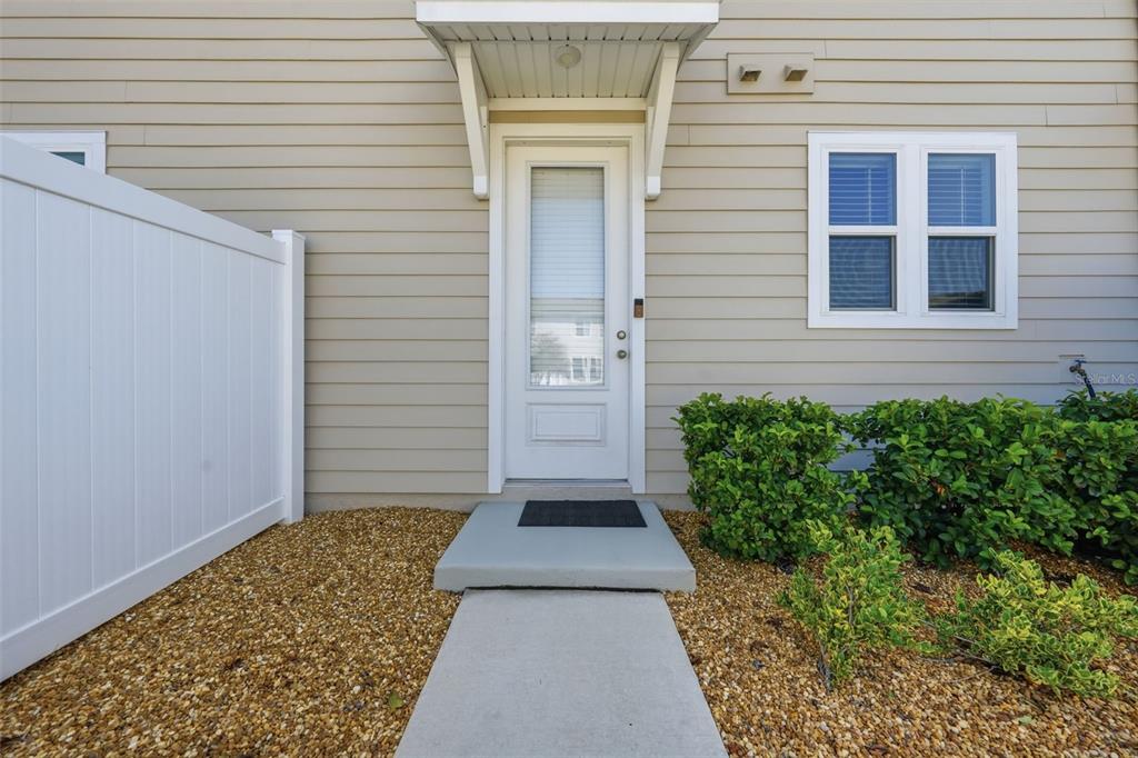 A white front door with a glass panel sits under a small awning on beige siding — 46 AXEL FALL DRIVE, ST JOHNS, FL