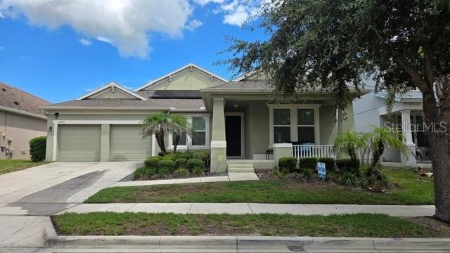A single-story house with a two-car garage, a front porch, and a small palm tree — 14776 MAGNOLIA RIDGE LOOP, WINTER GARDEN, FL