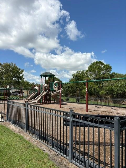 A fenced playground features a multi-level play structure with slides and a swing set — 14776 MAGNOLIA RIDGE LOOP, WINTER GARDEN, FL