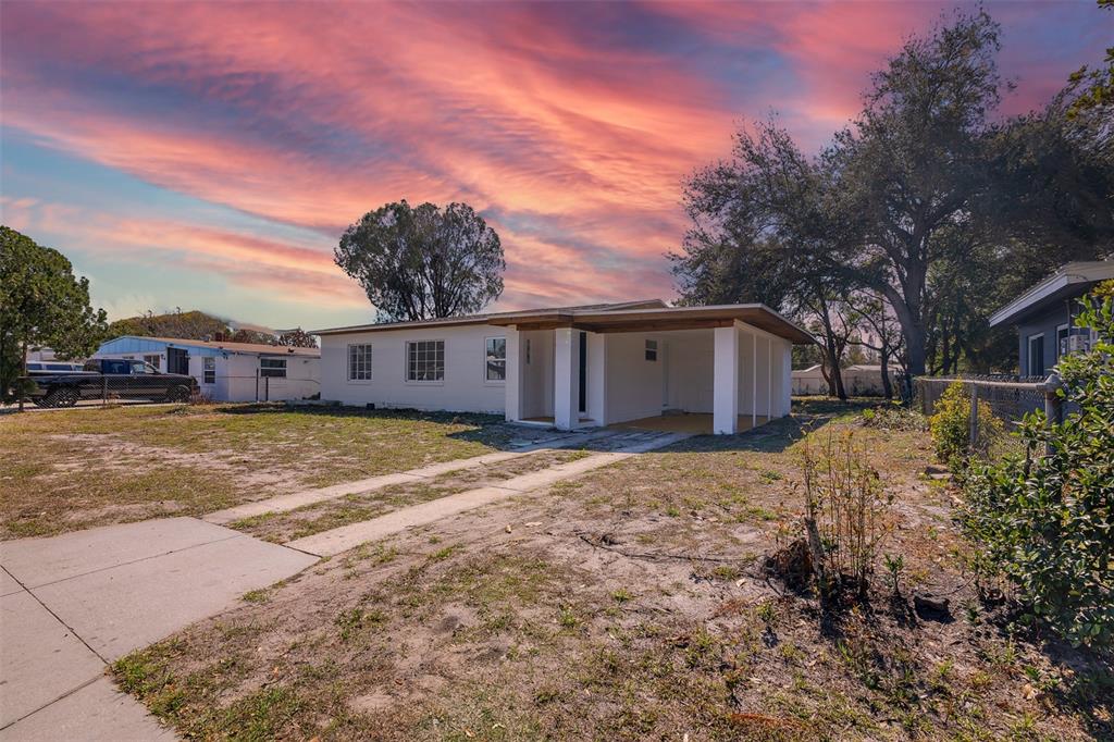 A single-story white house with a carport sits on a lot with a dirt driveway — 6146 DAHLIA DRIVE, ORLANDO, FL