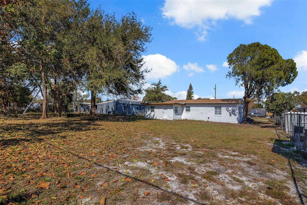 A white single-story house sits on a large, grassy lot with scattered leaves and trees — 6146 DAHLIA DRIVE, ORLANDO, FL